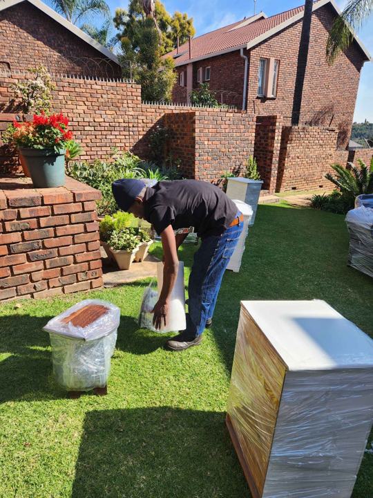 Crew member carrying boxes through a garden